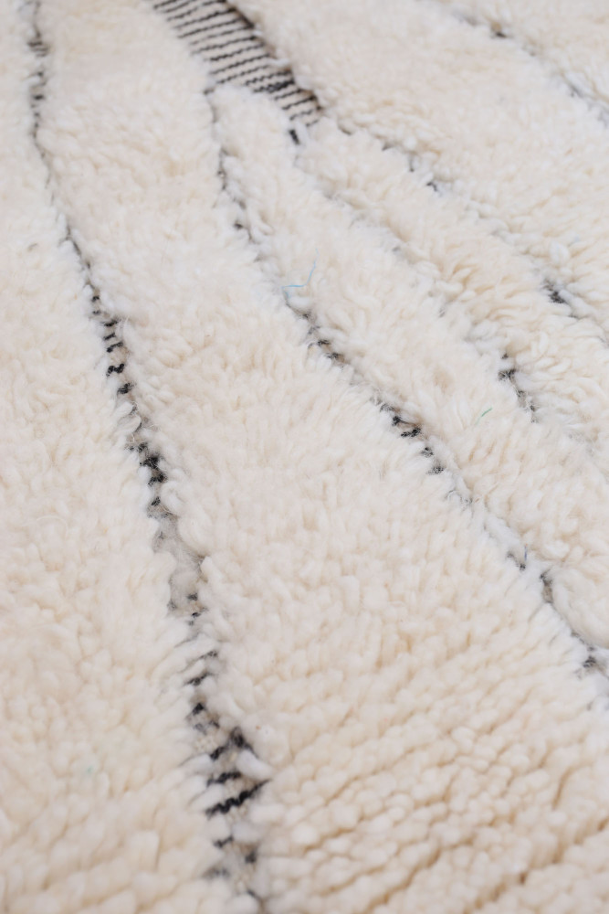Tapis berbère blanc avec des motifs noirs et une texture douce, apportant une touche d\'élégance rustique.