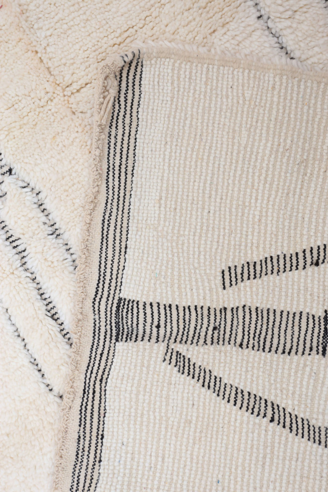 Tapis berbère en laine, style minimaliste, couleurs crème et noir avec motifs géométriques élégants.