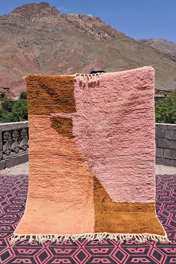 Tapis berbère aux couleurs pêche, rose et marron, avec des motifs géométriques et un design contemporain.