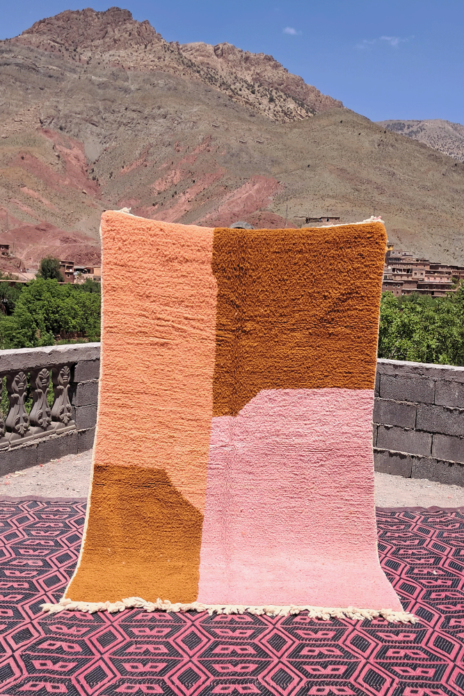 Tapis berbère moderne en couleurs pastel de rose, orange et marron avec des motifs géométriques uniques.