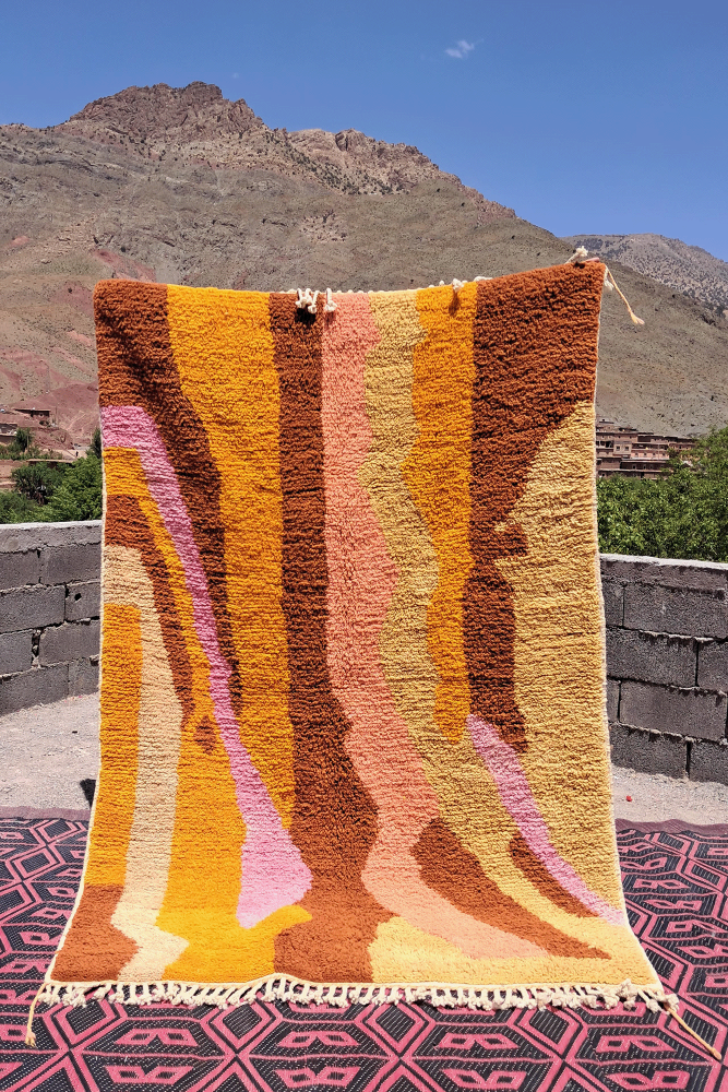 Tapis berbère aux motifs organiques, dans des teintes de jaune, orange, rose et marron, apportant une touche moderne.