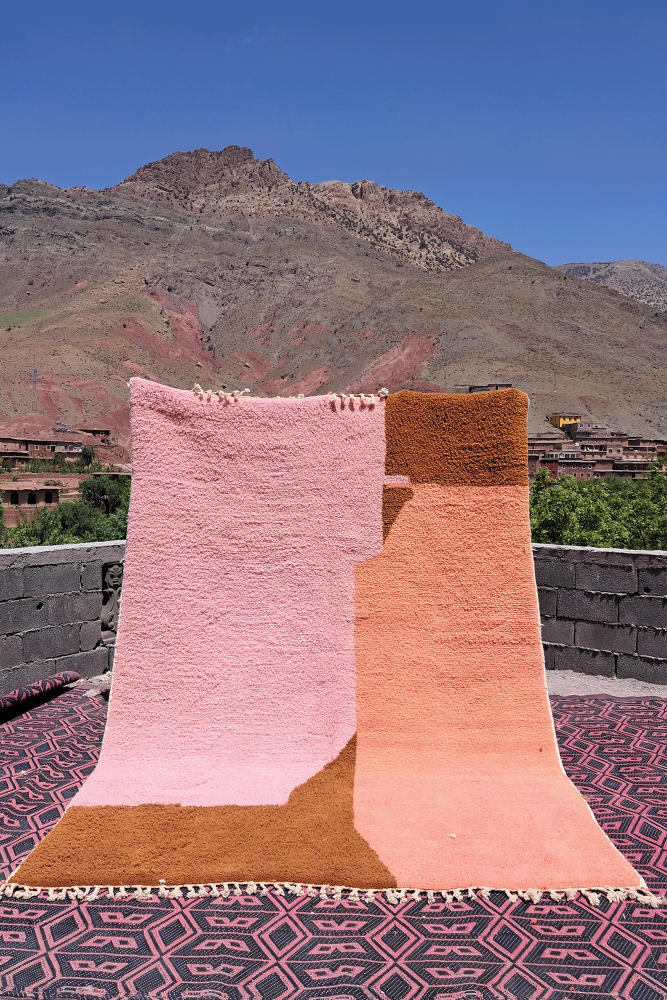Tapis berbère aux teintes douces de rose et ocre, avec un design minimaliste et des motifs géométriques subtils.