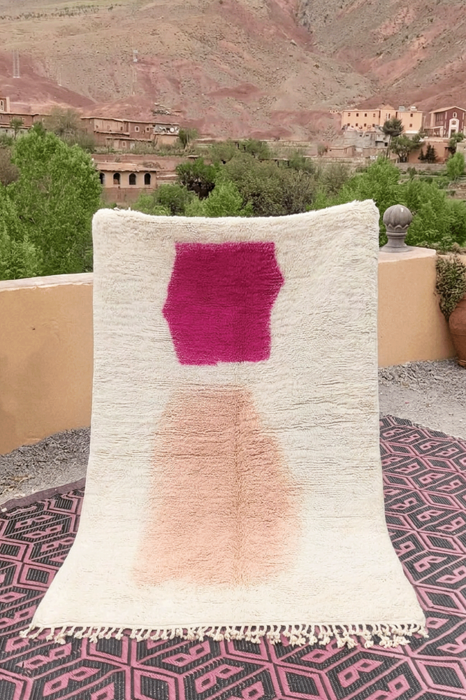 Tapis berbère au design moderne, couleurs crème, rose vif et motifs géométriques minimalistes.