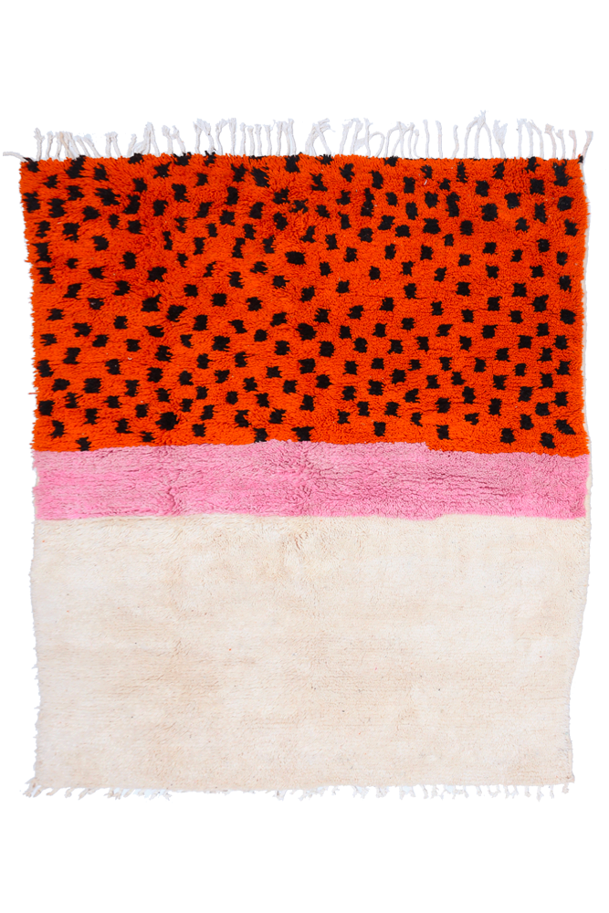 Tapis berbère coloré aux motifs géométriques, dominé par des teintes orange, rose et blanc.