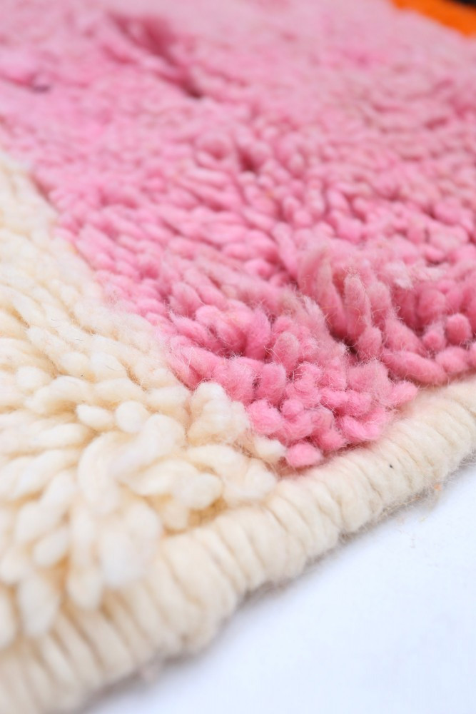 Tapis berbère aux teintes rose et crème, avec un motif doux et texturé.