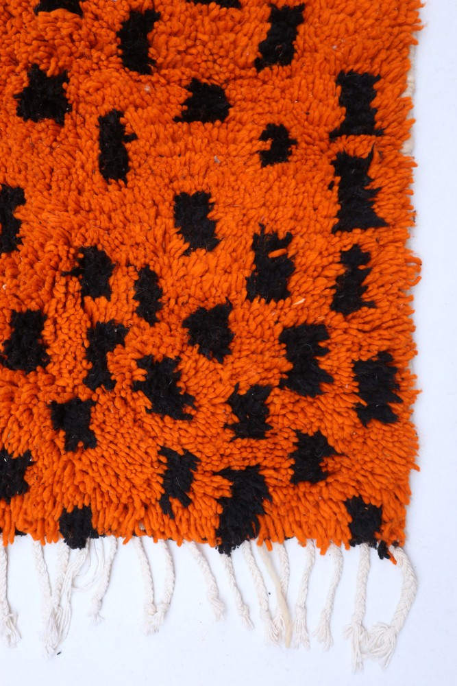 Tapis berbère en laine orange vif avec motifs noirs en pochoir, ajoutant une touche moderne et dynamique à n\'importe quel espac