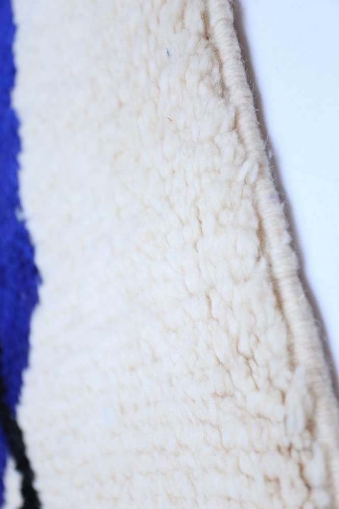 Tapis berbère au design géométrique avec des couleurs crème, bleu et noir, ajoutant une touche authentique à votre décoration.