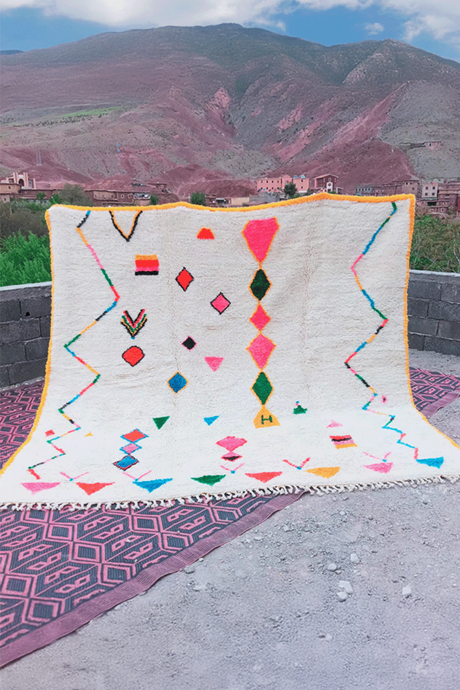 Tapis berbère aux couleurs vives avec des motifs géométriques sur fond crème.