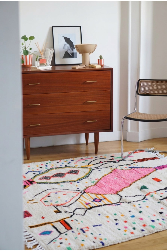 Tapis berbère coloré avec des motifs géométriques en rose, blanc et noir, ajoutant une touche bohème à votre intérieur.