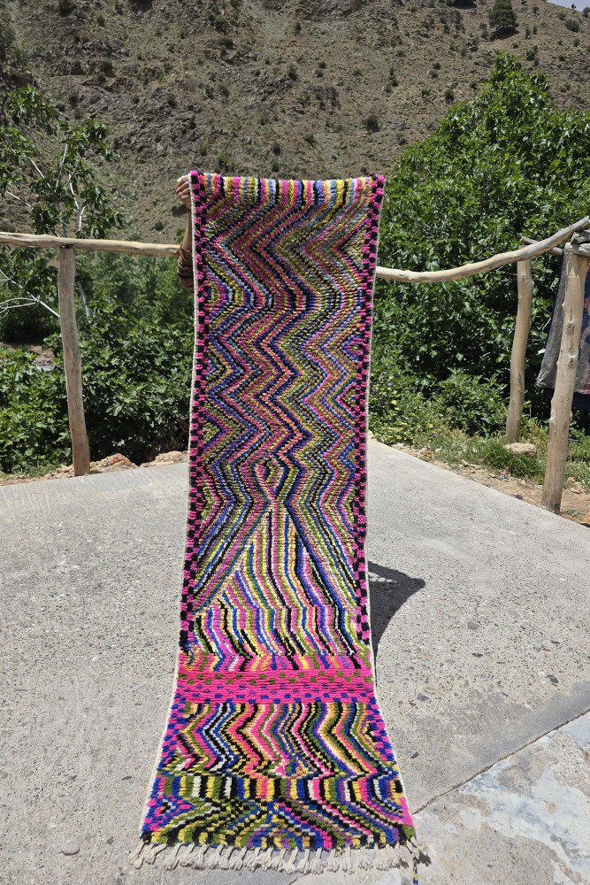 Tapis berbère aux motifs géométriques colorés de rose, violet, jaune et vert mêlant tradition et modernité.