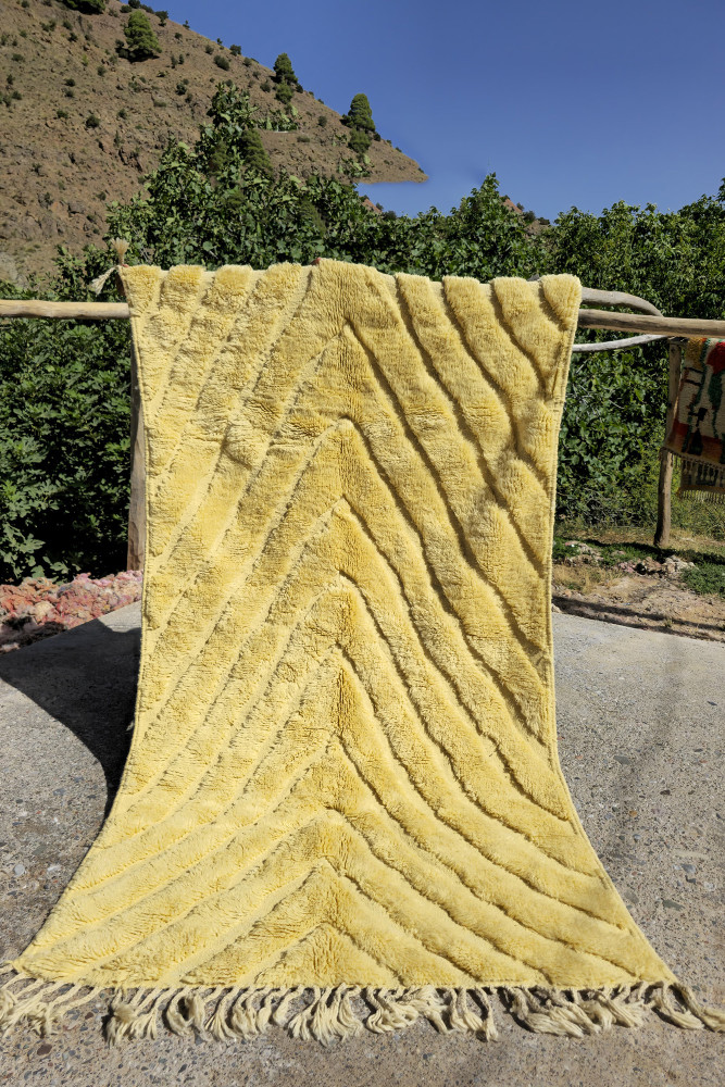 Tapis berbère jaune avec des motifs en zigzag et une texture douce, parfait pour ajouter chaleur et style à votre intérieur.