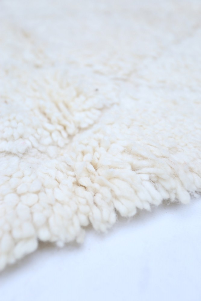 Tapis berbère en laine naturelle, couleur crème, au design tufté avec des motifs doux et texturés.