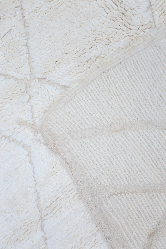 Tapis berbère blanc en laine, motifs géométriques délicats et texture douce, idéal pour un intérieur chaleureux.