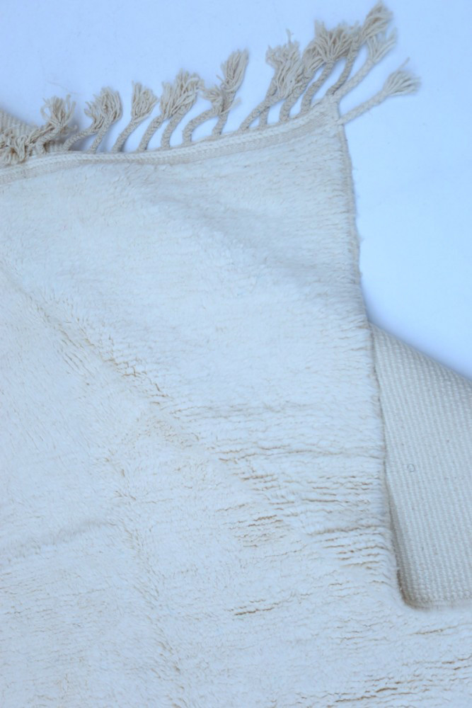 Tapis berbère aux teintes neutres, avec des motifs tissés, évoquant l\'élégance et le minimalisme.