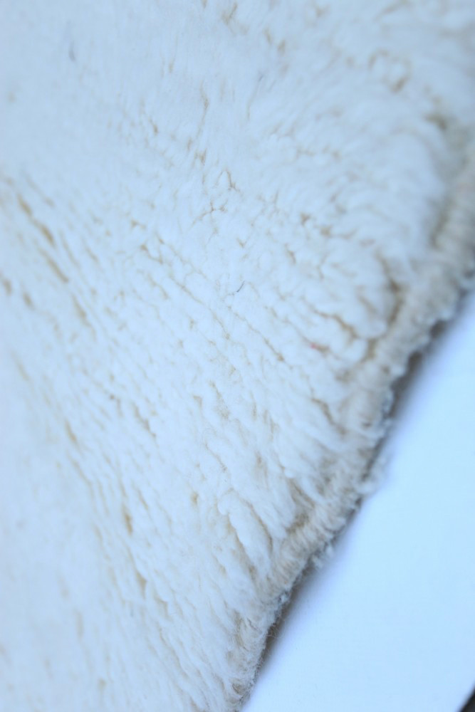 Tapis berbère artisanal en laine, couleur crème avec texture douce et motifs minimalistes idéal pour une décoration chaleureuse.