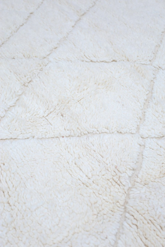 Tapis berbère en laine écrue, au design géométrique avec des textures douces et un aspect chaleureux.