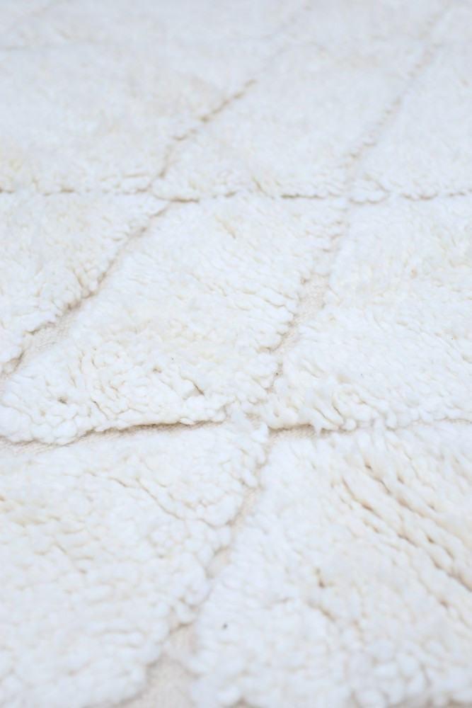Tapis berbère blanc en laine, au design géométrique avec des motifs en losange, ajoutant une touche scandinave élégante.