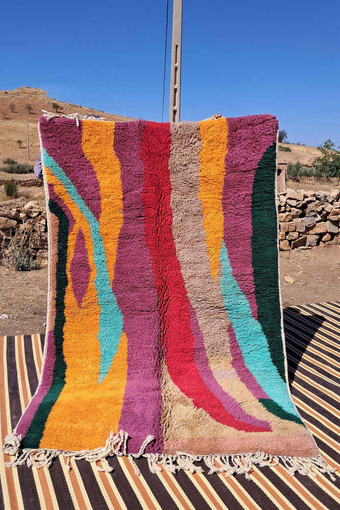 Tapis berbère aux motifs abstraits, couleurs vives comme le rose, orange, turquoise et beige.