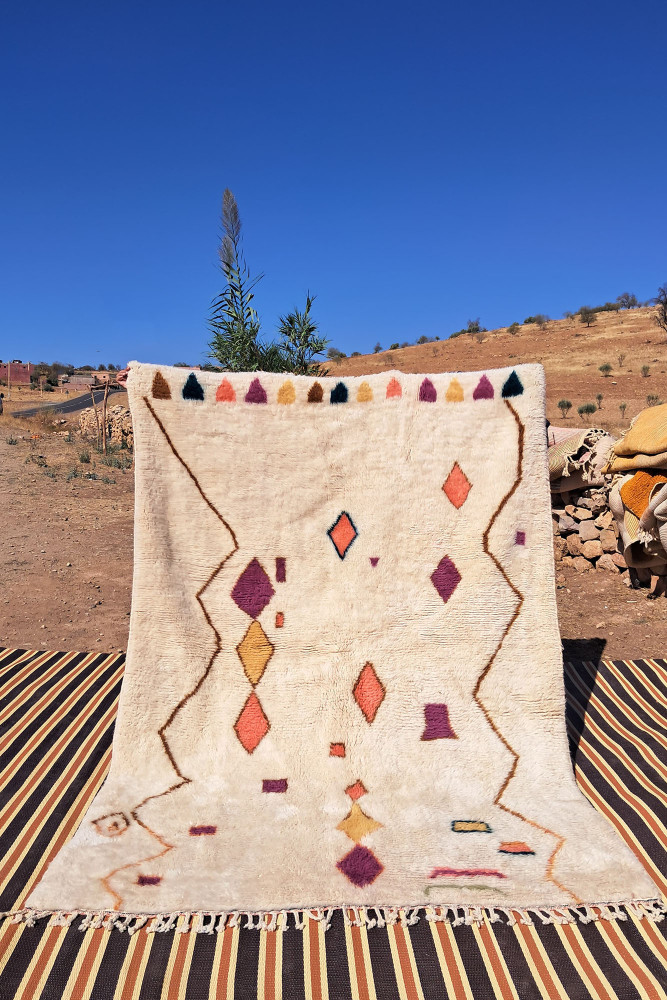 Tapis berbère aux motifs colorés, dominé par des teintes neutres et des formes géométriques vives.