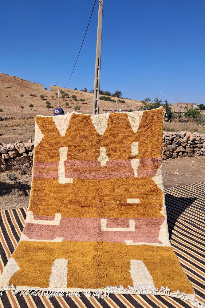 Tapis berbère aux couleurs terre et rose, motifs géométriques, ajoutant une touche artisanale et chaleureuse.