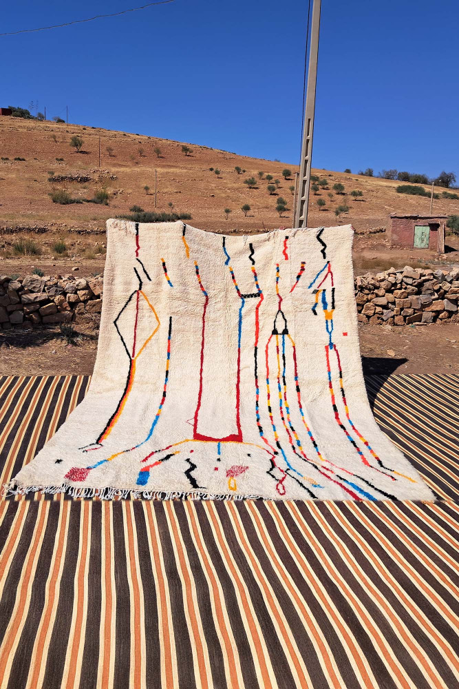 Tapis berbère au design contemporain, avec des motifs géométriques colorés sur fond crème.