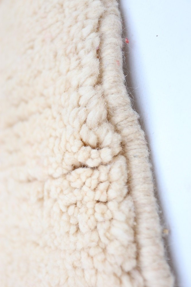 Tapis berbère en laine crème, au style traditionnel, avec un design texturé et des motifs subtils.