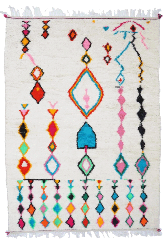 Tapis berbère aux motifs géométriques colorés, dominé par le blanc, le rose, le bleu et le noir.