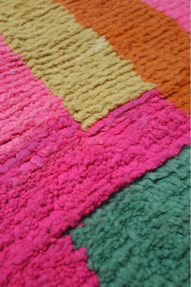 Tapis berbère aux couleurs vives, avec des motifs géométriques en rose, vert, orange et jaune, apportant une touche moderne.