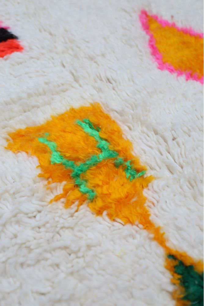 Tapis berbère aux motifs géométriques colorés avec du blanc, orange, vert et rose, parfait pour une décoration moderne.