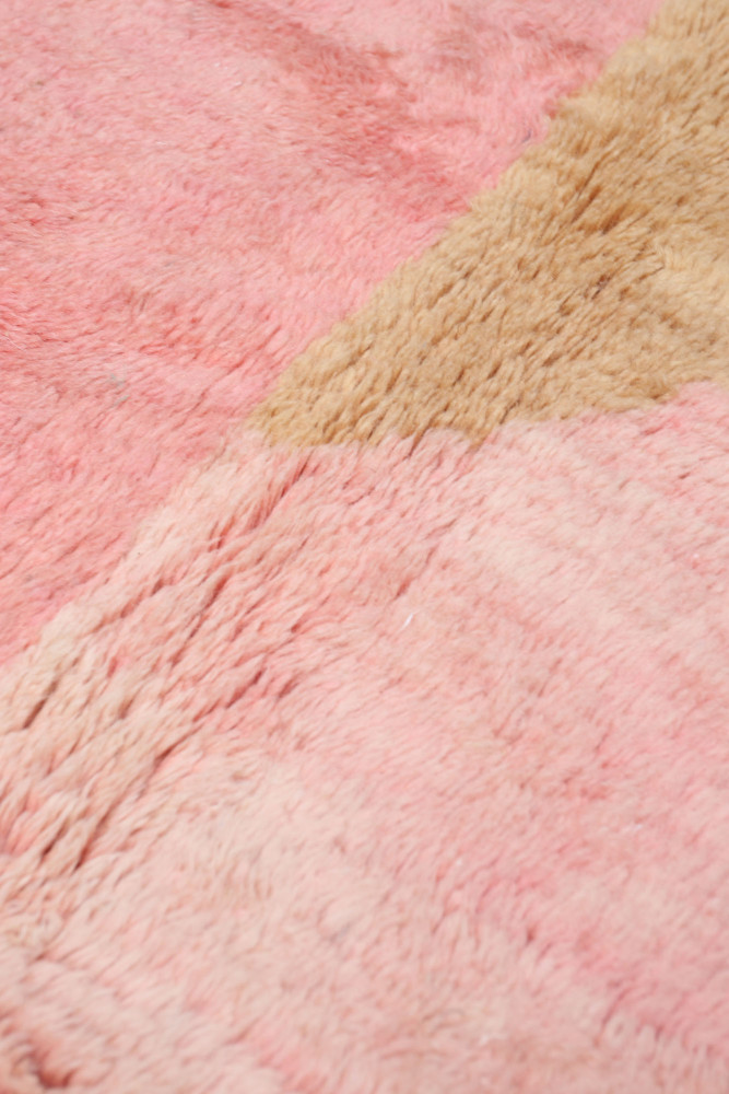 Tapis berbère rose et beige avec des motifs géométriques douillets et modernes.