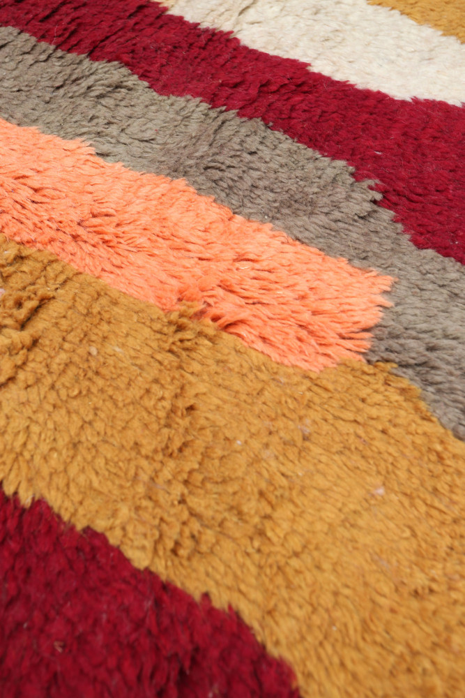Tapis berbère aux motifs géométriques, couleur rouge, orange, beige et marron.