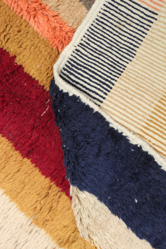 Tapis berbère aux motifs géométriques avec des couleurs rouge, bleu et beige.