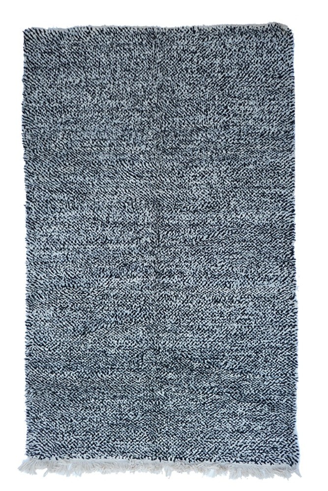 Tapis berbère en noir et blanc avec un motif texturé, apportant une touche moderne et chaleureuse à votre intérieur.