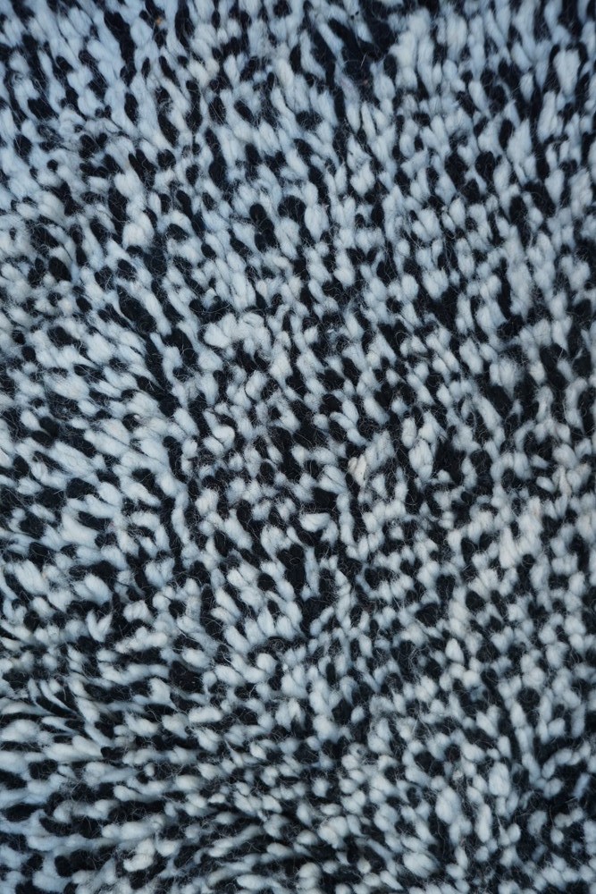 Tapis berbère en noir et blanc avec un motif texturé et des nuances de laine douces, idéal pour un décor contemporain.