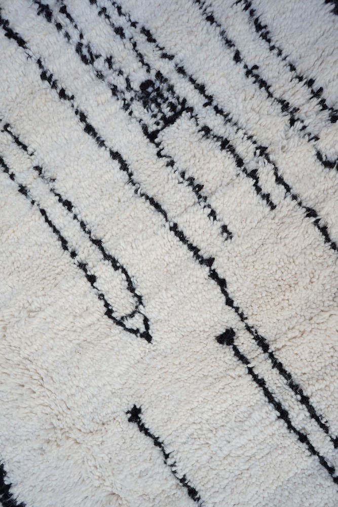 Tapis berbère stylé, aux couleurs crème et noir, avec des motifs géométriques modernes et texturés.